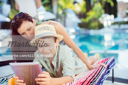 Mother and son using tablet pc by swimming pool