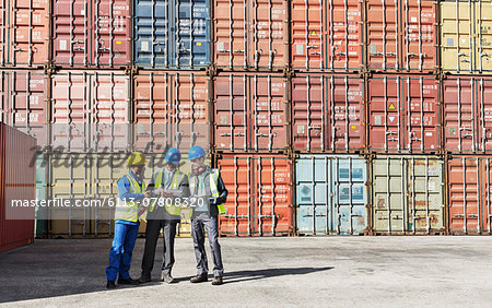 Worker and businessmen talking near cargo containers