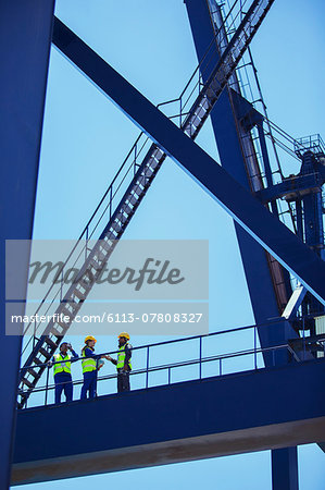 Low angle view of workers and businessman talking on cargo crane