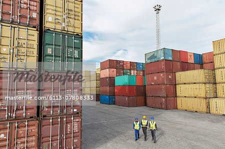 Businessmen and worker walking near cargo containers