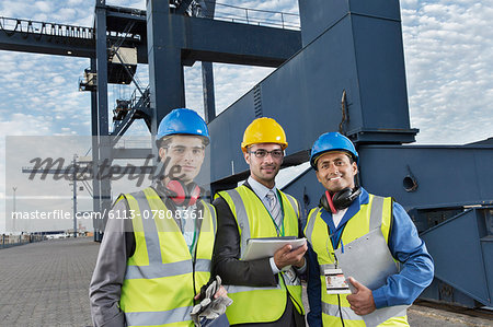 Workers and businessman smiling near cargo crane