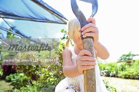 Girl holding shovel in sunny garden