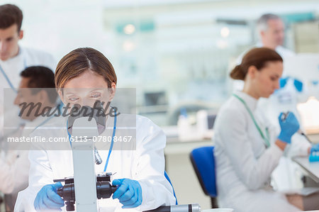 Scientist examining sample under microscope in laboratory