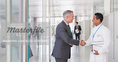 Scientist and businessman shaking hands in hallway