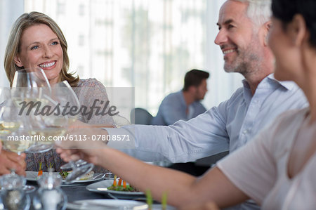 People raising a toast with white wine in restaurant