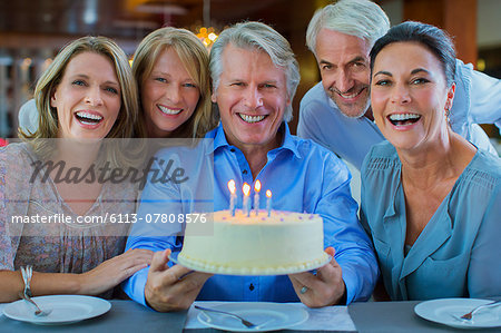 Portrait of smiling mature men and women with birthday cake Portrait of smiling mature men and women with birthday cake