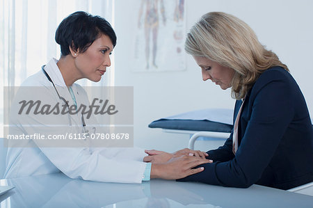 Female doctor consoling sad woman at desk in office