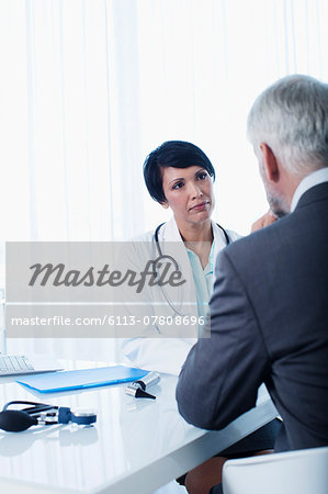 Female doctor and man sitting at desk in office