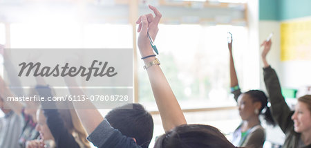 Teenage students with arms raised in classroom