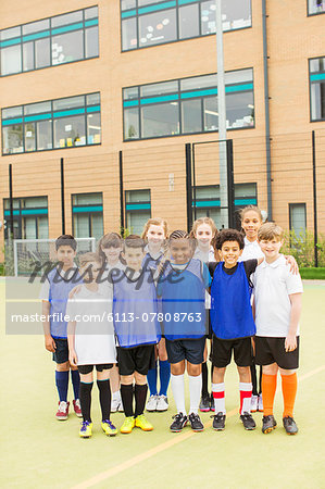 Group portrait of children wearing sport uniforms standing in front of school