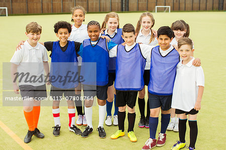 Group portrait of children wearing sport uniforms standing in school gym