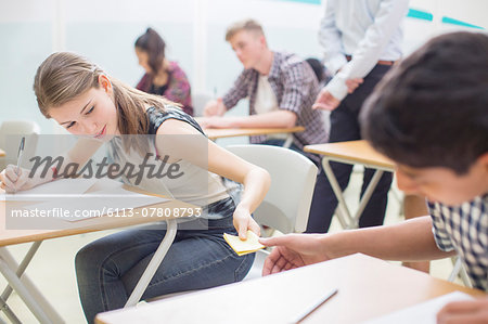 Students passing note between desks during their GCSE exam