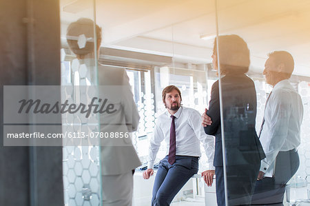 People having meeting in modern office seen through glass door