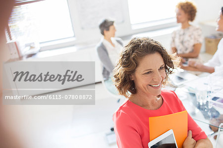 Portrait of woman with tablet in office, colleagues in background