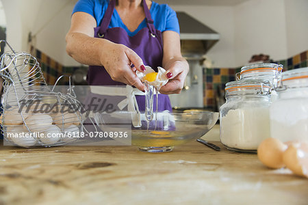A woman at a kitchen table baking fairy cakes.