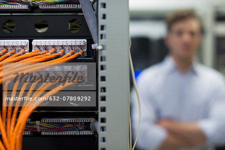 Network cables connected to computer mainframe, computer technician in background