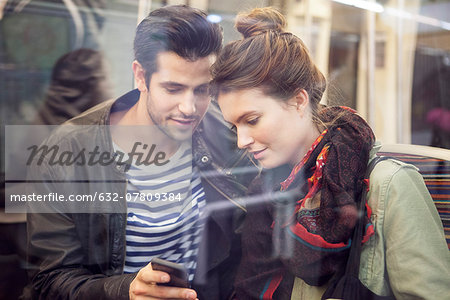 Couple on subway looking at smartphone together Couple on subway looking at smartphone together
