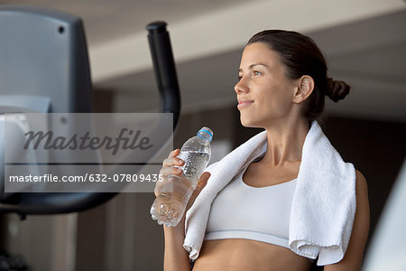 Woman holding bottle of water in health club