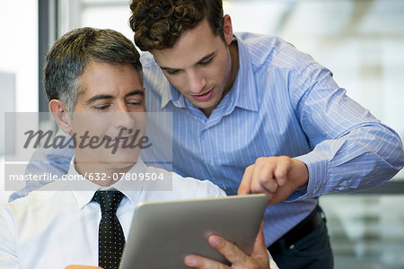 Assistant helping executive use digital tablet