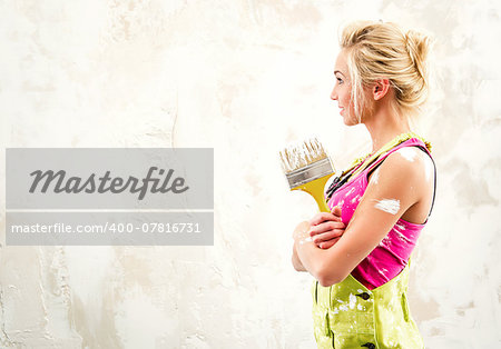 Female in coverall holding paint brush over white obsolete background