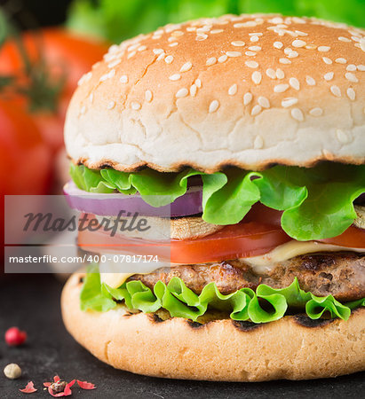 Burger with lettuce, onions, tomato and cheese on a sesame seed bun