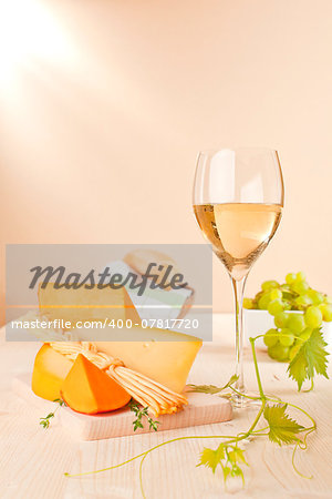 Traditional wine background. White wine, cheese and grapes on light wooden background. Culinary wine.