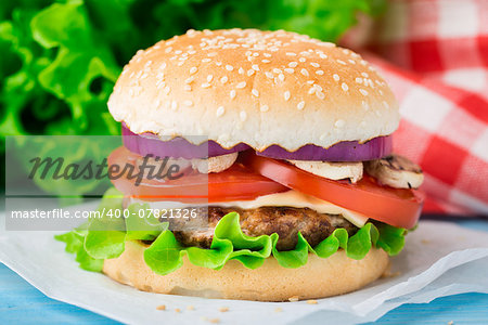 Burger with lettuce, onions, tomato and cheese on a sesame seed bun