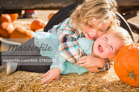 Sweet Little Boy Plays with His Baby Sister in a Rustic Ranch Setting at the Pumpkin Patch.