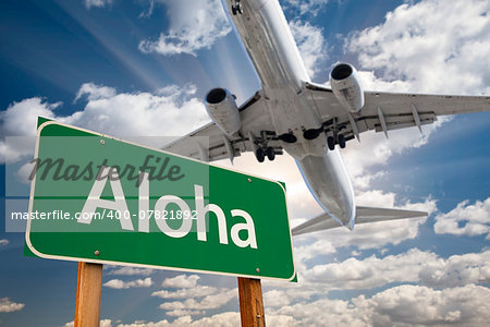 Aloha Green Road Sign and Airplane Above with Dramatic Blue Sky and Clouds.