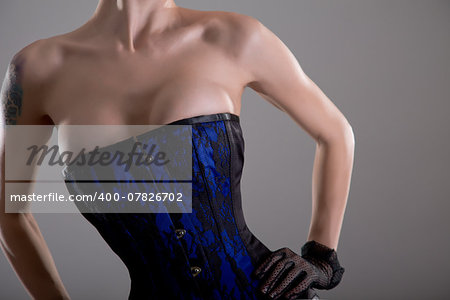 Busty young woman in black and blue corset with floral pattern, studio shot