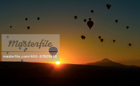 Silhouetts of hot balloons in morning sunrise and a mountain Erciyes. Cappadocia, Turkey