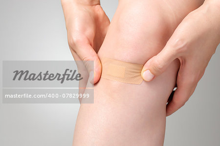 Woman putting an adhesive bandage on her leg