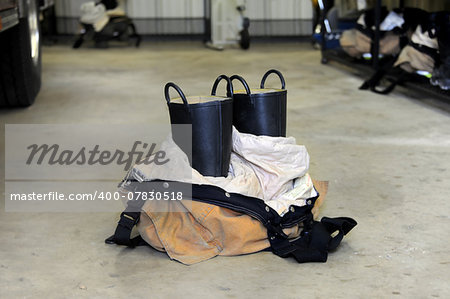 Bunking gear stands ready for fire fighter.  Black galoshes emerge from folded uniform.