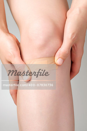 Woman putting an adhesive bandage on her leg
