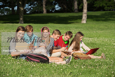 Cute group of students with books and laptop working outdoors