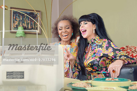 1960s style women laughing while watching television