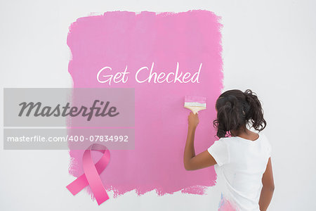 Young woman painting her wall in pink against pink breast cancer awareness ribbon