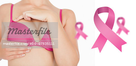 Closeup of woman performing self breast examination against pink breast cancer awareness ribbons