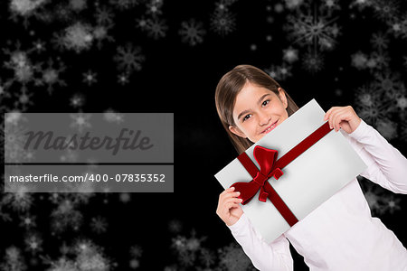 Cute little girl showing card against red christmas ribbon