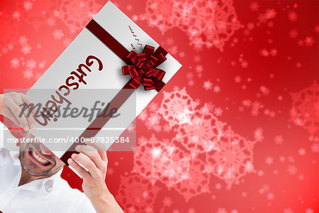 Festive man holding christmas gift against digitally generated delicate snowflake design