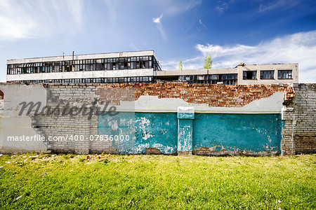 Abandoned factory behind old brick fence on a sunny day