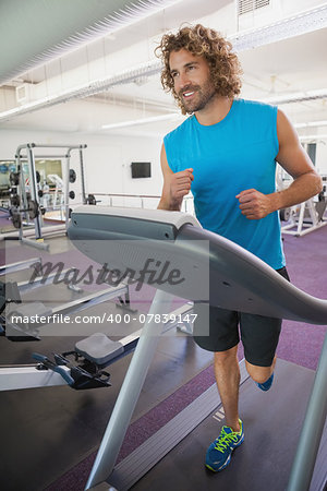 Smiling handsome man running on treadmill in the gym