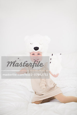 Girl wearing polar bear costume sitting on bed