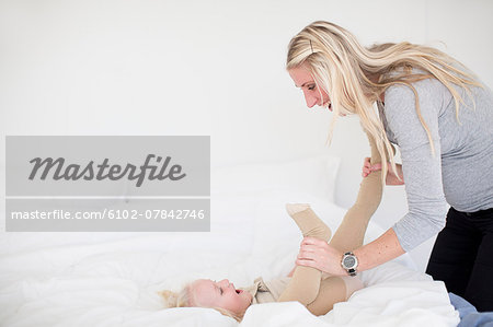Mother playing with daughter in bed