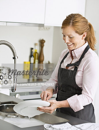 Smiling woman washing dishes