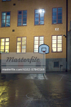 Basket hoop in front of school building at night