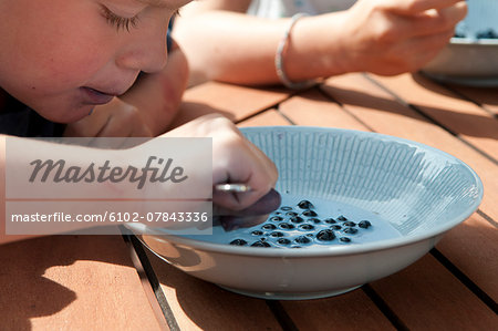 Boy eating milk with bilberries