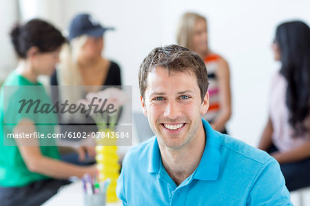 Portrait of smiling man, people on background