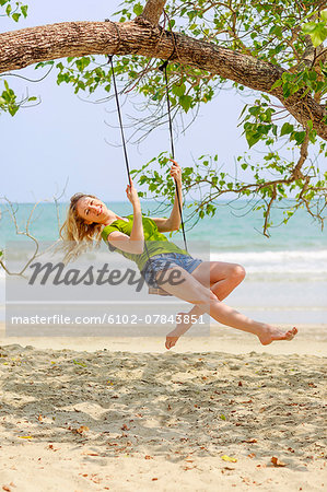 Young woman swinging at beach