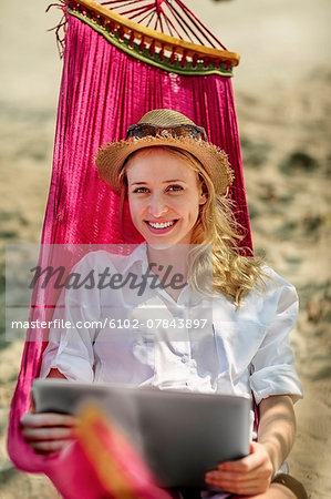 Portrait of young woman with laptop in hammock